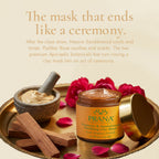 PRANA turmeric and sandalwood clay mask with rose petals, sandalwood pieces, and a golden lid on a beige background