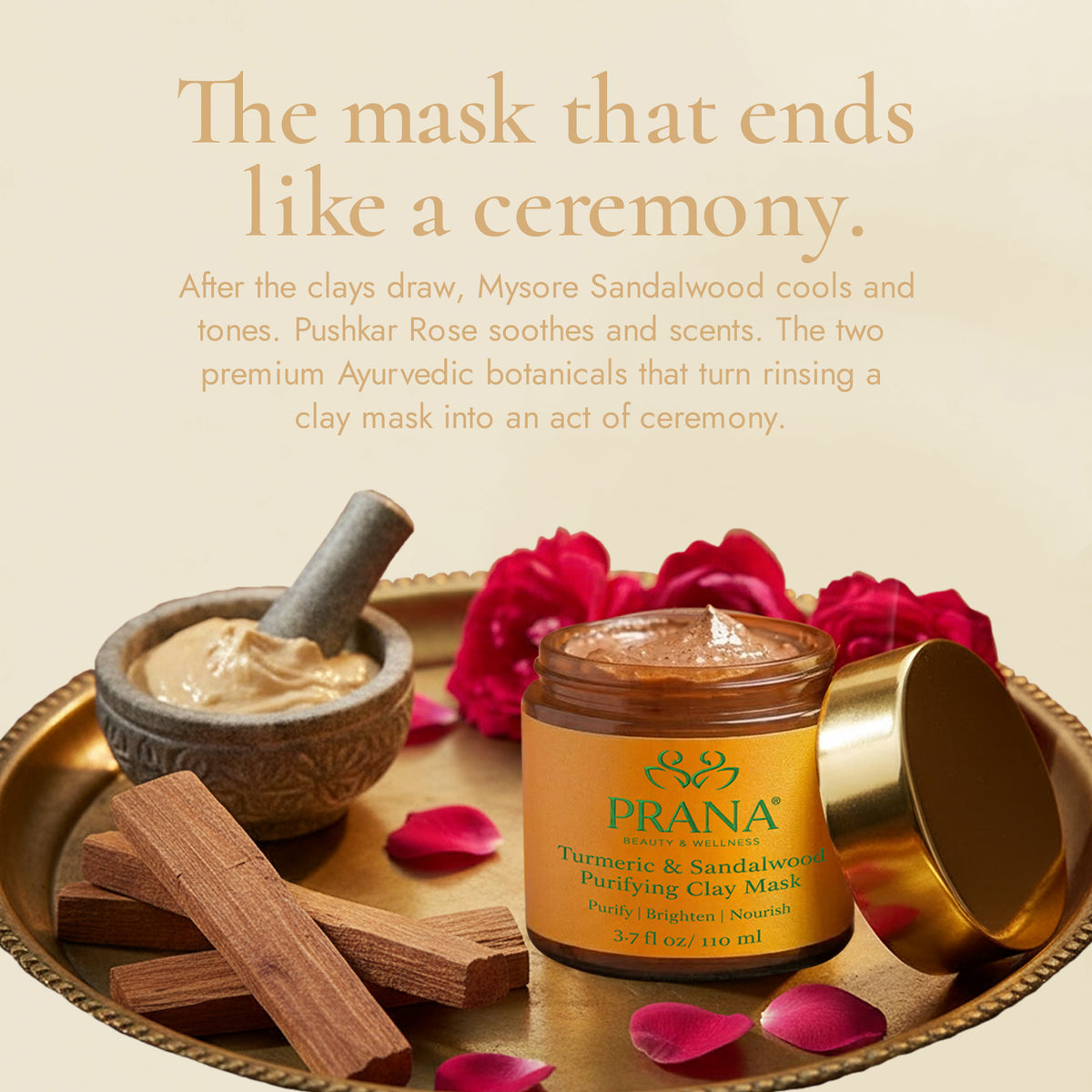 PRANA turmeric and sandalwood clay mask with rose petals, sandalwood pieces, and a golden lid on a beige background